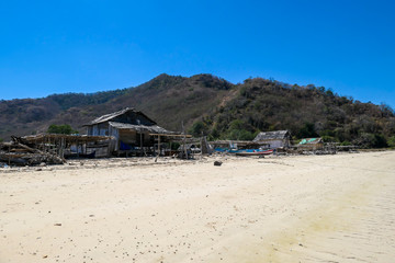 A distant view on a fishing cottage, located on a seashore of a small island next Flores, Indonesia. Houses located directly on the beach. Solitude and calmness. Simple construction