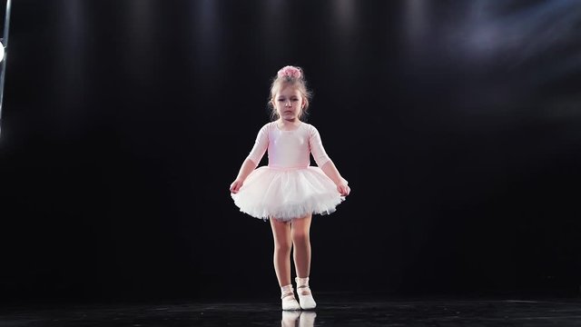 child ballerina in pink tutu dancing on the stage in the backlight. Children's ballet. Slow motion.