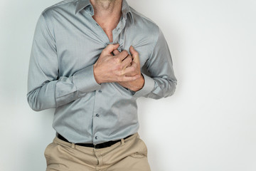 man in blue shirt and beige pants with his hands in his heart, expression of pain