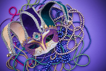 Fototapeta premium Festive mardi gras, venetian or carnivale mask on a purple background. Top view