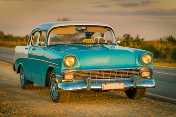 Obraz na płótnie Canvas colorful baby-blue cuban classic car in sunset light, cuba
