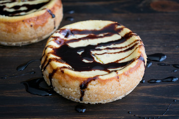 Mini Cheesecakes with Dark Chocolate Sauce: Pair of individual cheesecakes drizzled with dark chocolate sauce