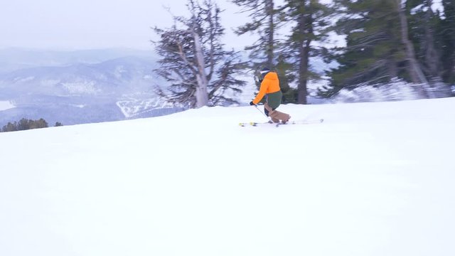 Professional skier rides on a mountain slope at a ski resort using telemark technique in slow motion