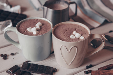 Two cups of hot cocoa with marshmallows and cinnamon sticks on wooden background. Love. Cocoa drink. Valentines day treat ideas.