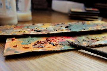 Fototapeta na wymiar Art palette. Close-up view. Artist's desktop. Workflow of the artist in the studio. Brushes and paints on art workplace.