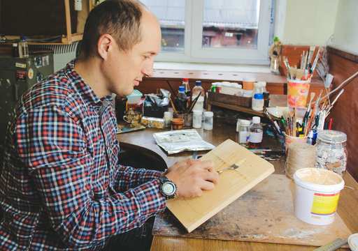 Putty knife in man's hand. The process of plastering in the workshop. Preparation of boards before impregnation or painting.