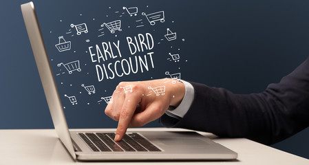 Businessman working on laptop with EARLY BIRD DISCOUNT inscription, online shopping concept