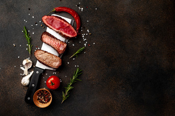 Three pieces of meat grilled over a meat knife. Three types of frying meat, rare, medium, well done with spices   on stone background with  copy space for your text