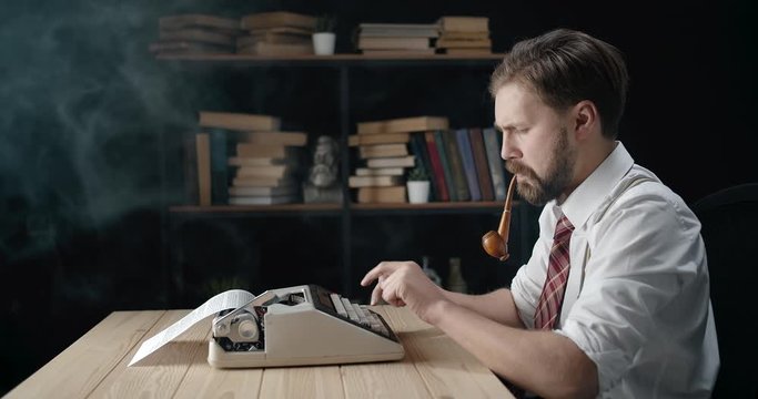 Bearded handsome writer in white shirt and tie working and smoking pipe, inspiration