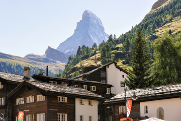 Traditional Swiss Chalets in Zermatt with Matterhorn peak with flags, Switzerland in summer.