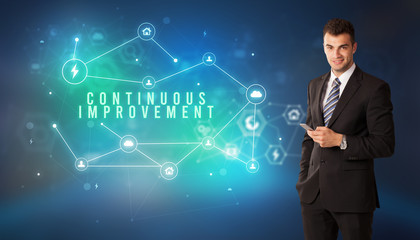 Businessman in front of cloud service icons with CONTINUOUS IMPROVEMENT inscription, modern technology concept