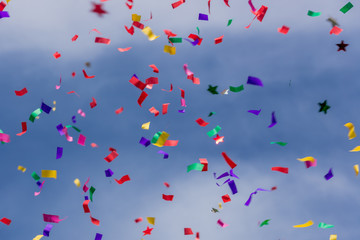 Colorful party confetti against a bright blue sky.