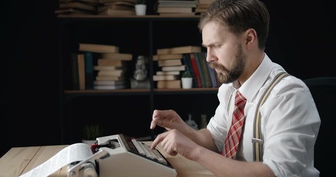 Energetic bearded middle-aged man typing on typewriter in old-fashioned room, writer having idea