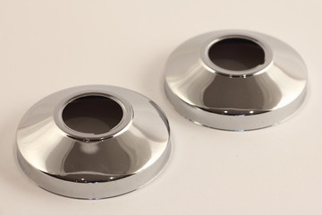 Two new decorative shiny chrome ring covers for faucet mounting in the bathroom wall, close up...