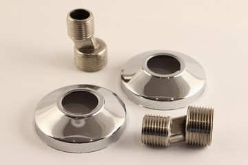 Eccentric adaptors with thread 1/2" - 3/4" and decorative chrome covers, faucet mounting kit in the bathroom wall, close up plumbing equipment on white background