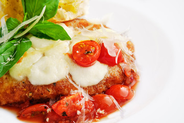 Closeup view of roasted chicken fillet with tomato cherry, parmesan and crouton on dark wooden background