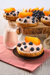 Closeup view of sweet buns with yogurt, blueberry and slice of persimmon on white wooden table