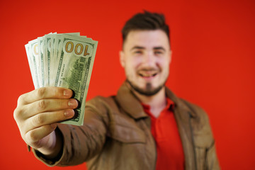 In the foreground, money is in focus in the hand, and in the background is a blurred image of a man.