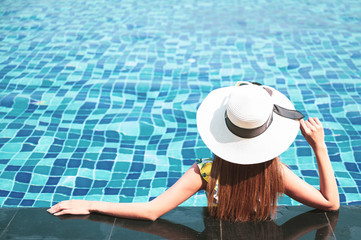 Summer and vacation concept. Young woman in sun hat relaxing in swimming pool.