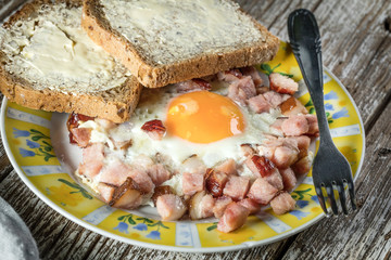 Fried eggs with ham on an old wooden background.