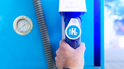 Man hold a fuel dispenser with hydrogen logo on gas station. h2 combustion engine for emission free...