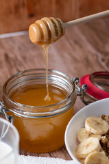 jar of honey and dipper on wooden background