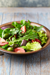 Salad with green Olives, Tomatoes and Cucumber on wooden Background. Healthy Snack Idea.
