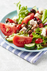 Healthy and tasty salad with feta cheese, various tomatoes, olives, cucumber, onion and lettuce.