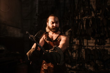 Fototapeta na wymiar Portrait of a brutal muscular blacksmith standing in a dark