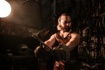 Fototapeta na wymiar Portrait of a brutal muscular blacksmith standing in the workshop