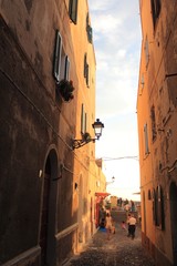 vicolo di Alghero, Sardegna, al tramonto; centro storico italiano con lampione e vecchie case