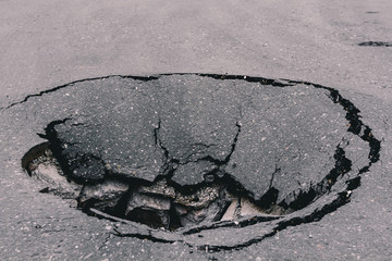 Deep sinkhole on asphalt with cracks