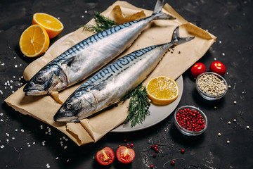 Mackerel with spices and herbs on a plate, fish still life on a dark background, assorted peppers, garlic, lemon, cherry tomatoes, dill