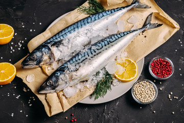Mackerel with spices and herbs on a plate, fish still life on a dark background, assorted peppers, garlic, lemon, cherry tomatoes, dill