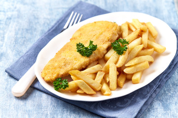 Pork Schnitzel with french fries on wooden background.