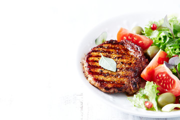 Grilled pork steak with fresh salad. White wooden background. Copy space. 