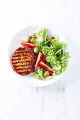 Grilled pork steak with fresh salad. White wooden background. Top view. 