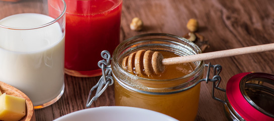 jar of honey and dipper on wooden background