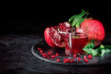 Glass of pomegranate juice and pomegranate fruit fresh garnet on dark background