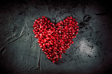 Heart shape pomegranate seeds on dark background