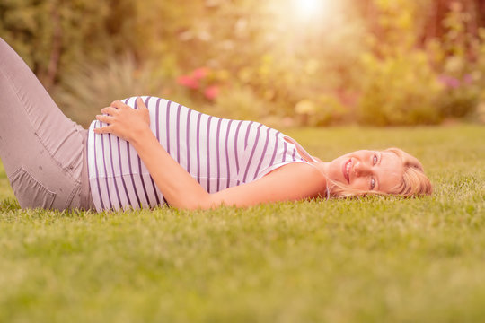 blonde expecting mom in nature on green meadow