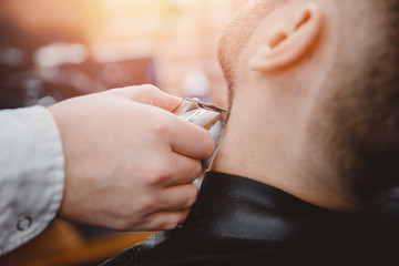 Barber shearing beard to man in barbershop framing hairline. electric razor, vintage tinted brown