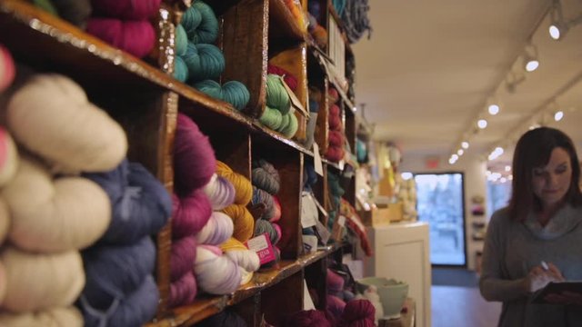 Yarn shop owner taking inventory with digital tablet
