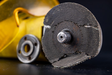 Damaged cutting disc for metal in an angle grinder. Power tools in a locksmith's workshop for repair.