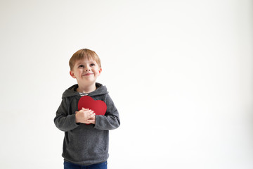 Sweet boy holding red paper heart on white background. Valentines day or kids healthcare, medical concept