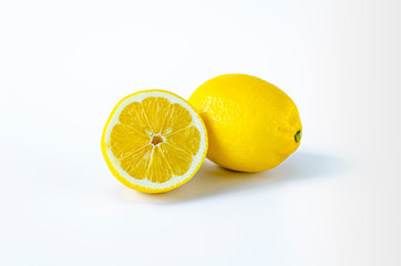 Half a lemon and a whole lemon on a white background