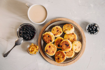 Curd pancake with tea and jam for breakfast. Plate of cottage cheese with raisins on a light background. Healthy Food, Quick Breakfast Recipe