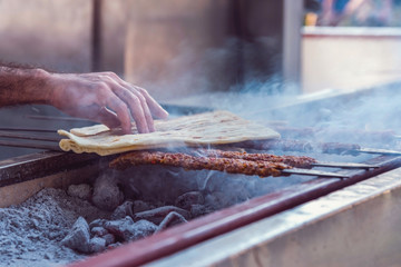 Traditional  Turkish kebab grilling on  barbecue with two pita breads on it, close up, food photography