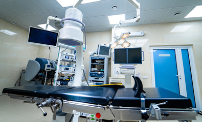 Establishing shot of technologically advanced operating room with no people, ready for surgery. Operating theater with working equipment, lights and computers ready for surgeons.