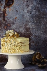 A great white and gold birthday cake on the cake stand on the dark vintage background. Happy Birthday concept